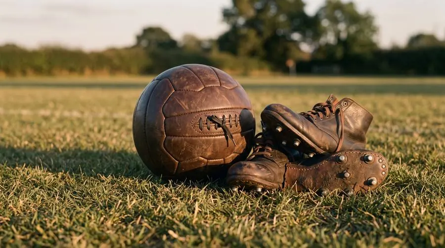 Alter Lederfußball und Fußballschuhe im Gras